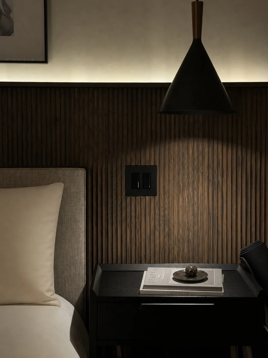 Bedside lighting control integrated into dark wood paneling