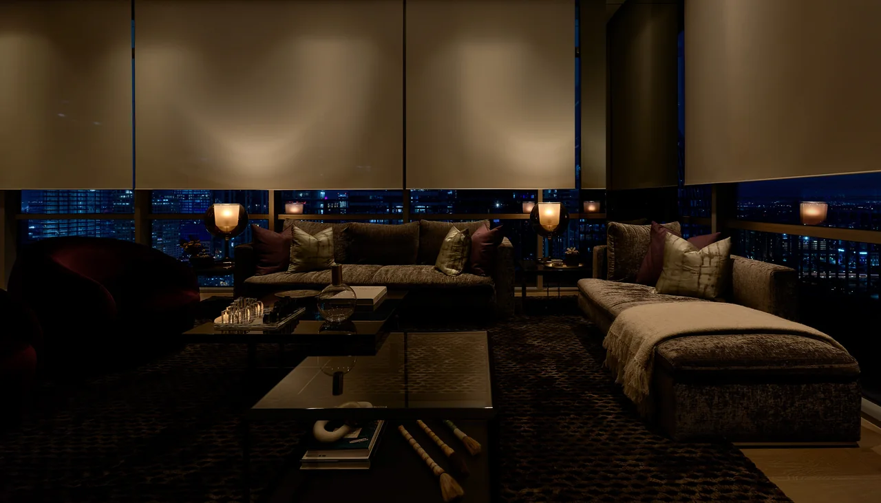 Motorized shades across the windows of a city residence at night
